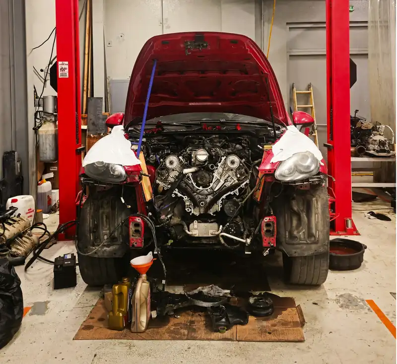 A car on a lift in a repair bay with its hood open.
